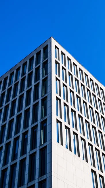 Des laveurs de vitres en hauteur, équipés de matériel de sécurité, nettoient la façade d’un gratte-ciel.